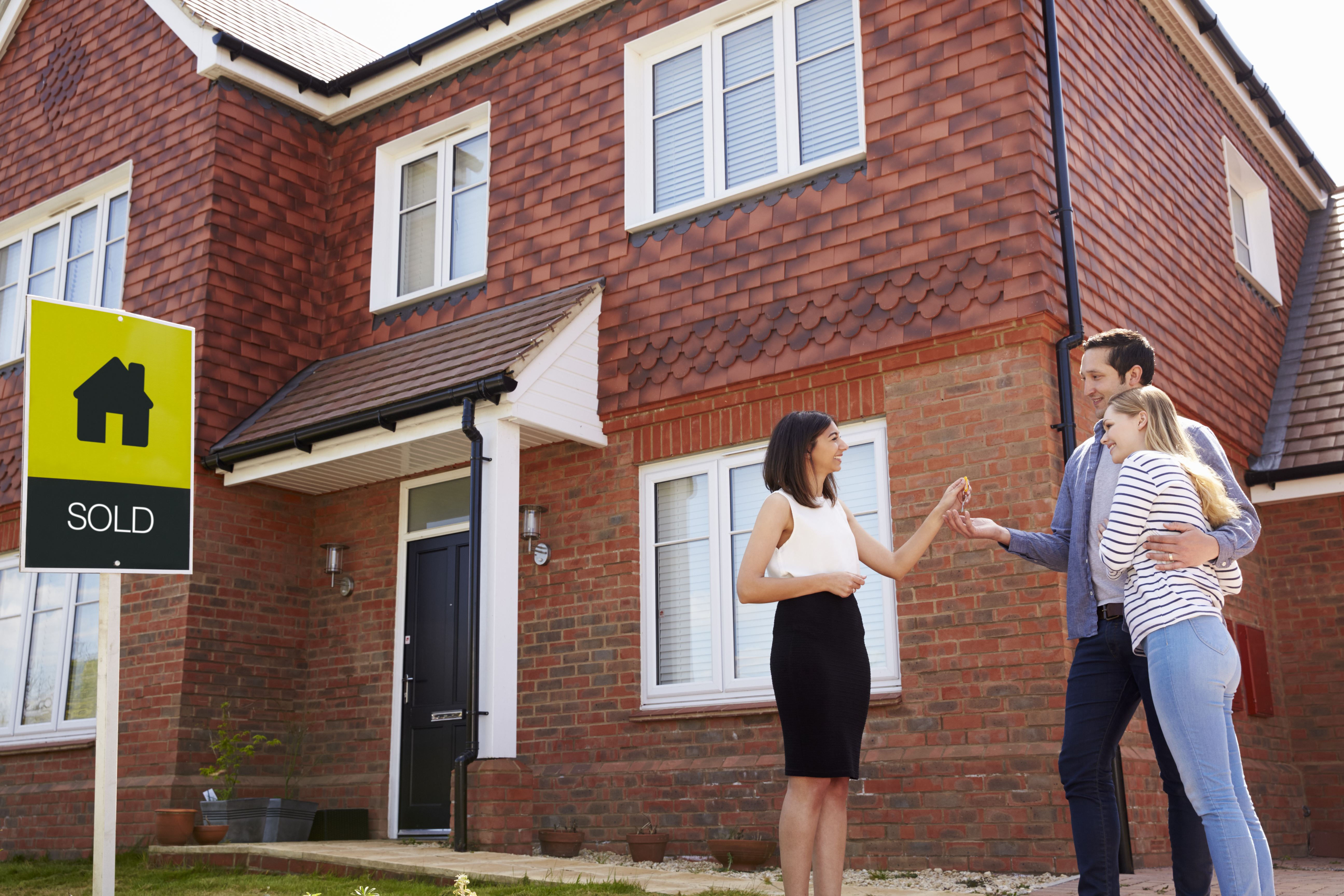 Couple receiving house keys outside a sold property